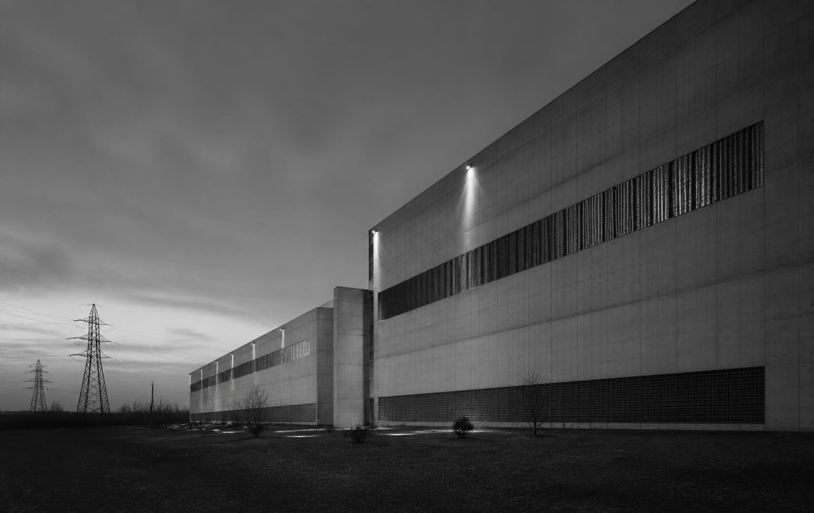 Large-scale data centre facility beside high-voltage transmission infrastructure at dusk